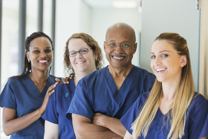 A group of nurses smiles together in a bright corridor in Lewisville, TX