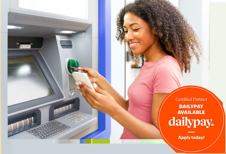 A woman stands near a cash machine, looking at her phone in Lewisville, TX